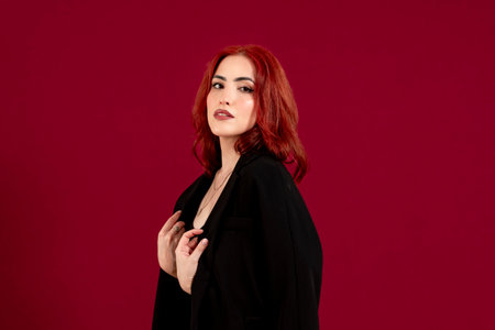 Confident woman looking at the camera and smiling while posing against a red isolated background.の写真素材