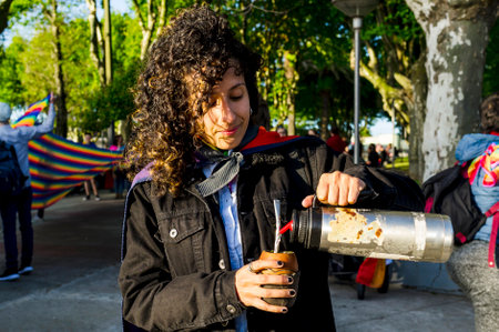 Woman drinking mate and holding a rainbow flag in an lgbtq pride march.の写真素材