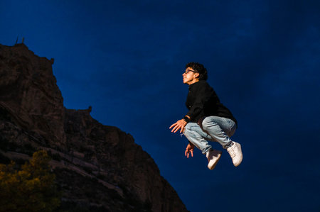 Young transgender man jumping outdoors at night.の写真素材