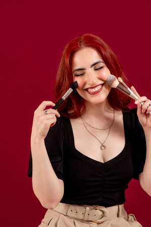 Stylish woman holding make-up brushes while posing against an isolated background.の写真素材
