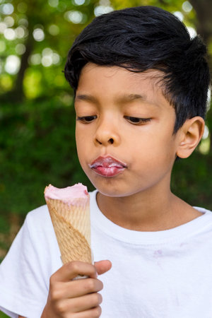 Close-up of a young boy eating ice-cream outdoors in a park.の写真素材