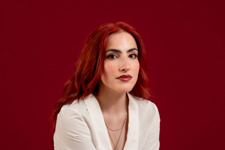 Confident woman looking at the camera and smiling while posing against a red isolated background.の写真素材