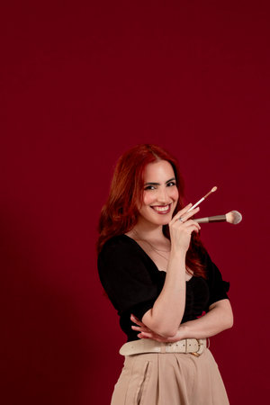 Stylish woman holding make-up brushes while posing against an isolated background.の写真素材