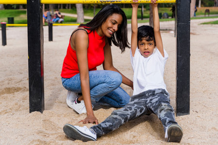 Mother and son enjoying playing at the playground in the park.