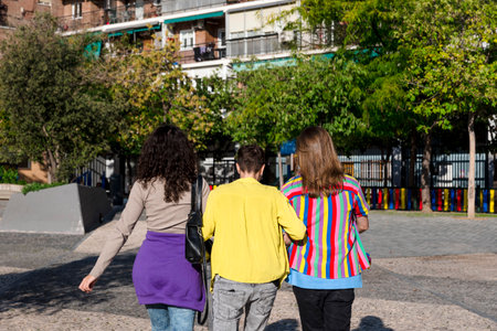 Young friends embracing while walking outdoors with the lgbt rainbow flag.の写真素材