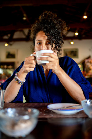 Relaxed woman smiling and drinking a cup of coffeeの写真素材