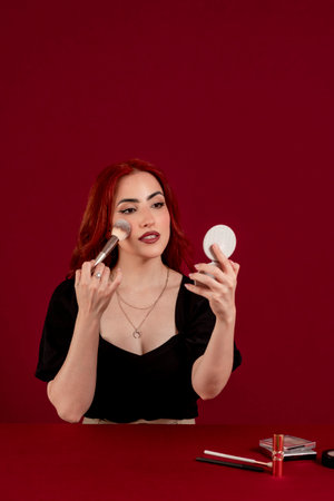 Woman applying makeup on her face against a colored isolated background.の写真素材