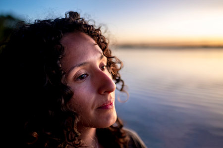 Mixed-race thoughtful woman enjoying outdoors at sunset.の写真素材