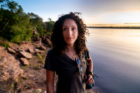 Mixed-race thoughtful woman enjoying outdoors at sunset.の写真素材