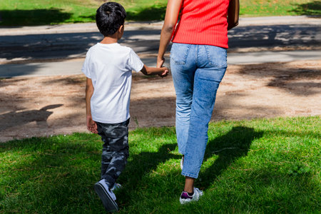 Happy mother and son walking together outdoors in a park.の写真素材