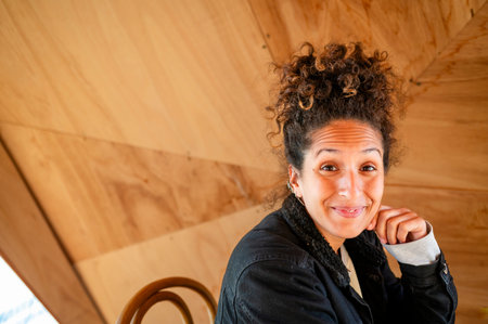 Happy Latin woman smiling while sitting indoors.