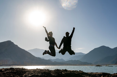 Couple jumping and enjoying a natural landscape of mountains and lake.の写真素材