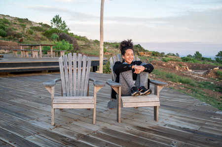 Relaxed woman sitting on a deck in the nature during sunset.の写真素材