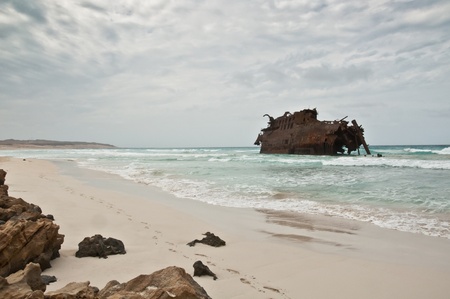 Shipwreck worned out by the wether and the waves of the ocean on the coast of the island of Boa Vista in Cape Verde on a cloudy and rainy dayの写真素材