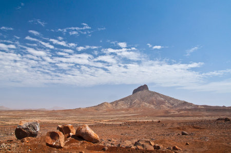 Lonely hill in the endless desert of Boa Vista with blue sky in the background and huge stones in...