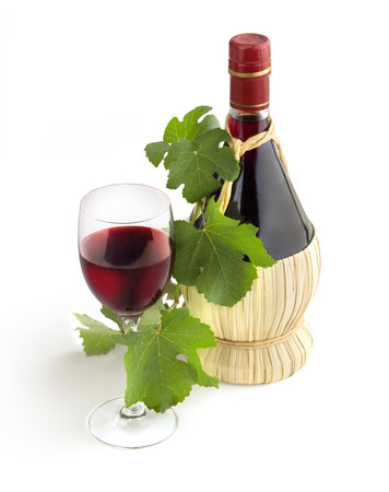 classic Chianti bottle, wineglass and grapevine leavesの写真素材