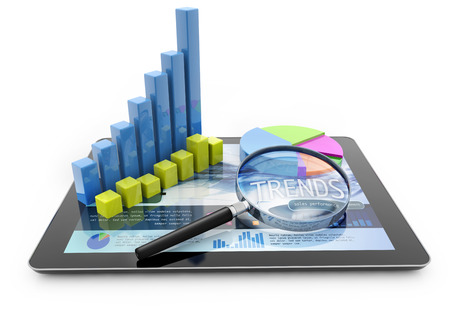 graphs and magnifier over a portable computer on white backgroundの写真素材