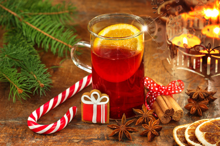 glass of mulled wine, ingredients and candy cane on wooden backgroundの写真素材