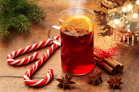 mulled wine and candy canes by candlelight on wooden tableの写真素材