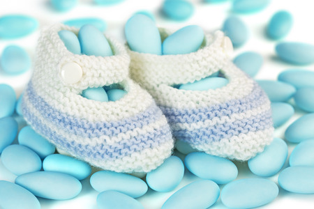 crochet baby booties over blue sugared almondsの写真素材
