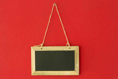 blank chalkboard hanging on the red wallの写真素材