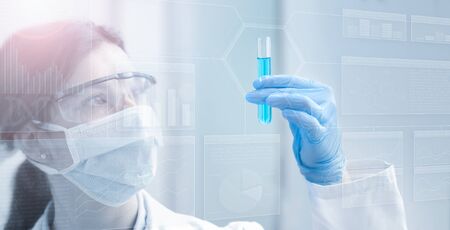 Woman chemist holding a test tube in light blueの写真素材