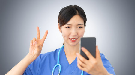 beautiful asian female doctor takes a selfie gesturing the victory sign with her fingers, confident...