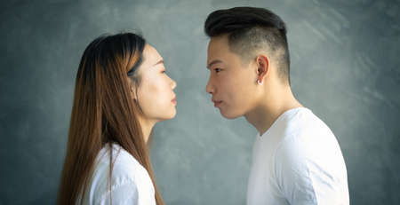 young asian couple is experiencing conflict, they look into each other's eyes intensely after quarrelの写真素材