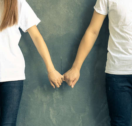 young couple in jeans and t-shirt holds hands affectionatelyの写真素材