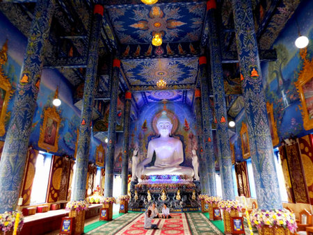Chiang Rai. Thailand, June 16, 2017: Wat Rong Suea Ten. Three people are photographed inside the Blue Temple in Chiang Rai with the Buddha image and colorful decoration on the walls. Thailandのeditorial素材