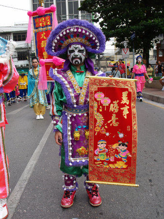Bangkok, Thailand, November 14, 2015: A man in costume and face paint carrying a banner in the...