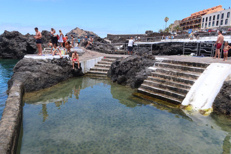 Garachico, Tenerife, Canary Islands, Spain, July 6, 2022: Tourists sunbathing in one of the El Caleton natural pools, Garachico, Tenerife. Spainのeditorial素材