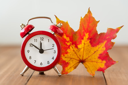 Red vintage clock and mable leaf. Autumn time changeの写真素材