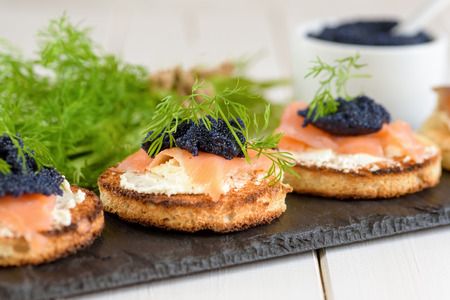 Appetizer toast with cream cheese, smoked salmon and black caviar decorated by dill.の写真素材