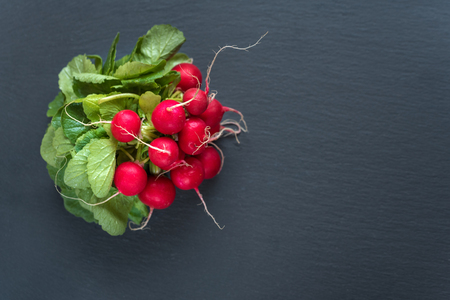 Bunch of radish with leaves on black background. Top view, copy space.の写真素材