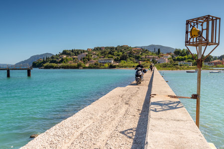 CORFU, GREECE - May 13, 2016: Young woman riding a scooter through causeway. Corfu island, Greeceのeditorial素材