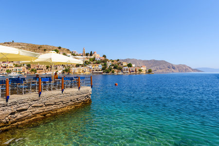 SYMI, GREECE - May 15, 2018: View of coastal tavern overlooking blue sea. Symi island, Greece