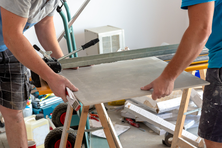 Men working with floor tile cutting equipment at renovation work. Home renovation.の写真素材