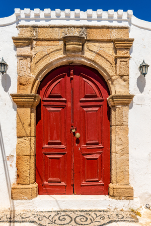 Red door in traditional Greek house in historic village of Lindos on Rhodes island. Greece.の写真素材