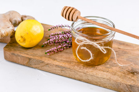 Honey in jar with fresh heather on wooden background