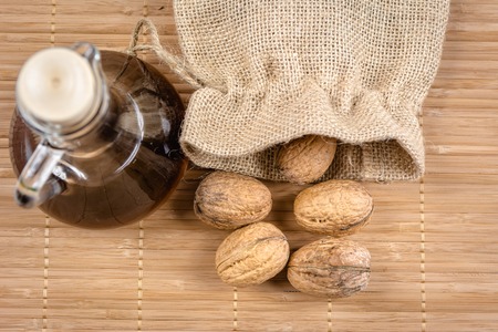Fresh walnuts in a burlap bag and bottle with walnuts tincture.の写真素材
