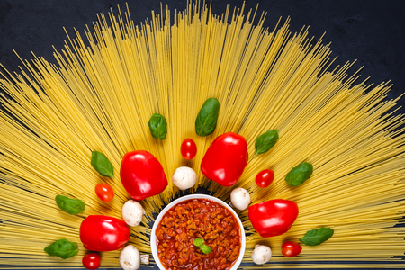 Spaghetti with ingredients for cooking pasta on a black background. Top view.の写真素材