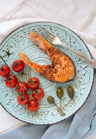 Fried salmon served with caper apples and cherry tomatoes.の写真素材
