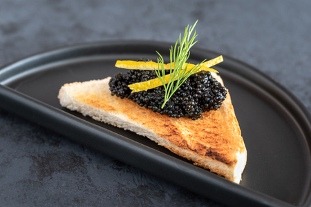 Appetizer toast bread with black caviar decorated by lemon pill and dillの写真素材
