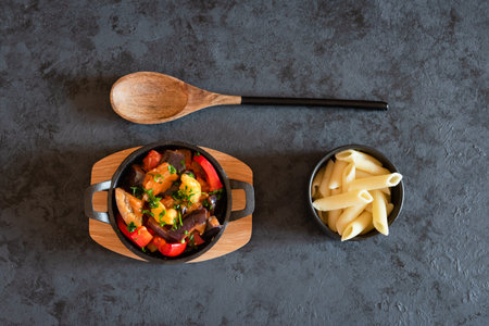 Vegetarian letcho with baked aubergine, zucchini, pepper in tomato sauce. Dish served with pasta.
