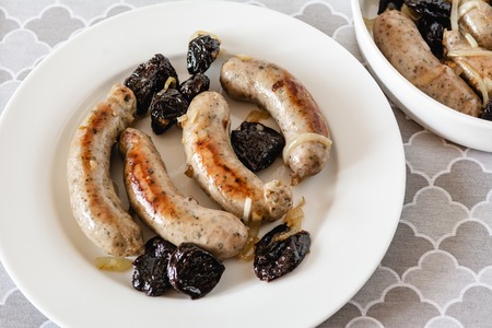 White sausage fried with onions and dried plums.の写真素材