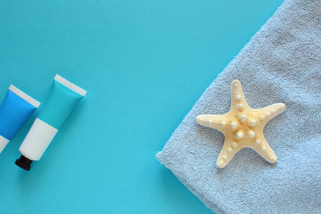 Summer holiday concept with starfish and cosmetics on the blue background.