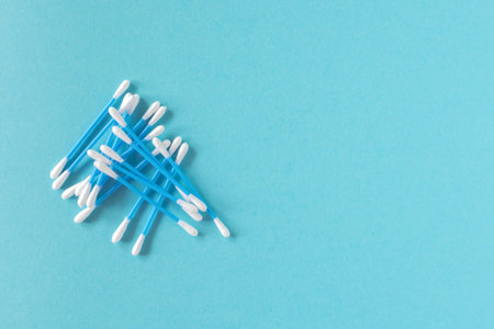 Cotton ear sticks for personal hygiene on blue background. Healthcare tools. Empty space for text.