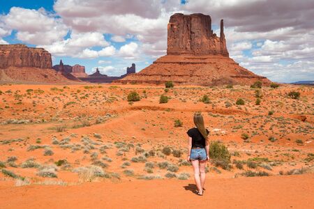Young woman standing near famous red rocks of Monument Valley. Navajo Tribal Park landscape, Utah/Arizona, USAの写真素材
