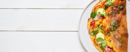 Omelette with zucchini, lamb's lettuce, tomatoes and red pepper on white plate. Frittata - italian omelet. Flat layの写真素材